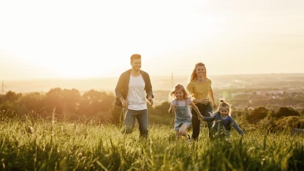 Eine Familie rennt über eine Wiese im goldenen Abendlicht.