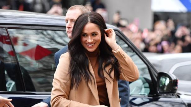 Meghan Markle verlässt ein Auto in einem beigen Mantel und braunen Schuhen.