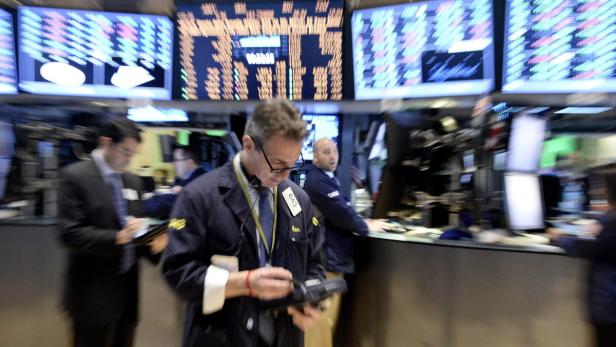 Händler arbeiten an der New Yorker Börse vor Anzeigetafeln.