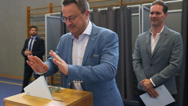 Der luxemburgische Premierminister Xavier Bettel (C) und sein Ehemann Gauthier Destenay (R) bei der Stimmabgabe in einem Wahllokal im Rahmen der Parlamentswahlen in Luxemburg am 8. Oktober 2023 