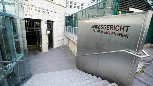 Eingang zum Landesgericht für Strafsachen Wien mit Treppen, Glasgeländern und Beschilderung.