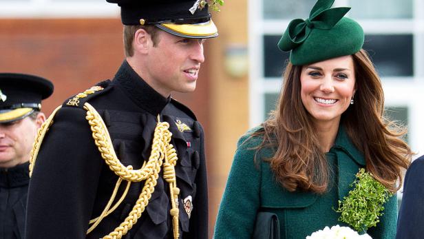 Prinz William in Uniform und Kate Middleton mit grünem Hut lächeln.
