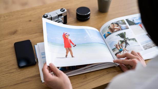 Eine Person blättert in einem Fotoalbum mit Urlaubsbildern.
