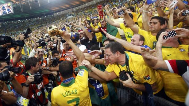 Brazil&#039;s Lucas holds up the trophy as he celebrates with supporters after winning their Confederations Cup final soccer match against Spain at the Estadio Maracana in Rio de Janeiro June 30, 2013. REUTERS/Kai Pfaffenbach (BRAZIL - Tags: SPORT SOCCER)