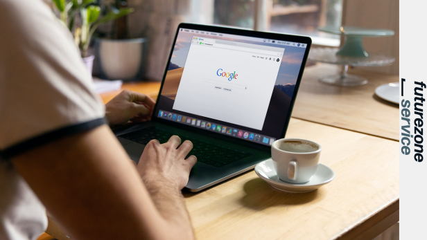 Eine Person benutzt einen Laptop mit der Google-Startseite neben einer Tasse Kaffee.