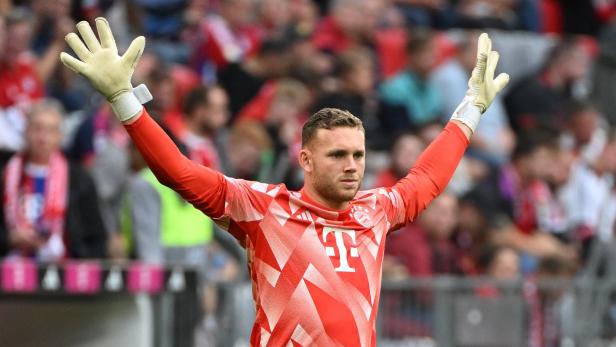 Ein Torwart des FC Bayern München streckt die Arme mit Handschuhen in die Höhe.