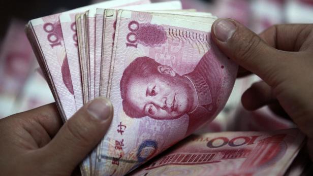 Hände halten einen Stapel chinesischer 100-Yuan-Banknoten.