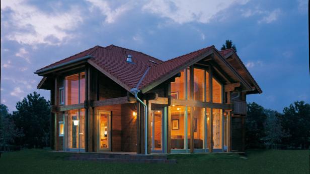 Ein modernes Holzhaus mit großen Fenstern in der Abenddämmerung.