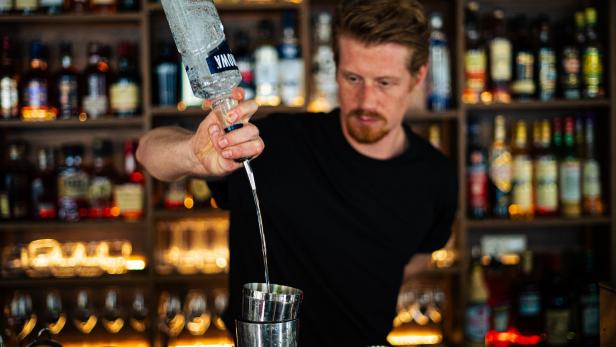 Ein Barkeeper gießt Wodka in einen Shaker.