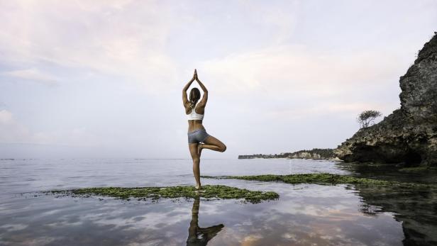 Frau praktiziert Yoga am See.