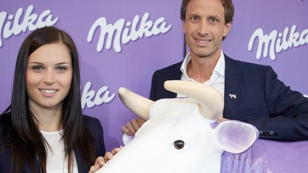 Die Fußballerin Celia Šašić und ein Mann posieren mit einer Milka-Kuh.