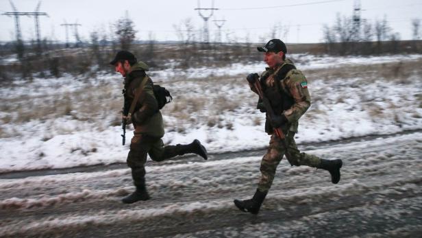 Zwei bewaffnete Soldaten rennen auf einer verschneiten Straße.