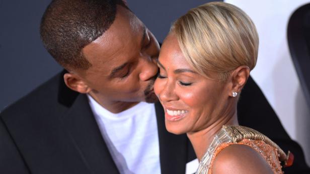 Will Smith küsst Jada Pinkett Smith auf die Wange.