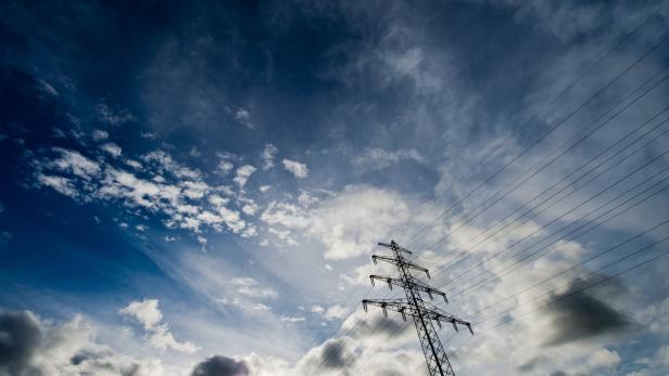 Ein Strommast steht unter einem Himmel mit Wolken.