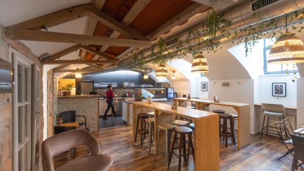 Innenansicht eines Restaurants mit Holzböden und einer Person im Hintergrund.