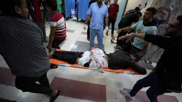 Injured people are assisted after Israeli air strike hit At Al-Ahli Hospital, according to Gaza Health Ministry
