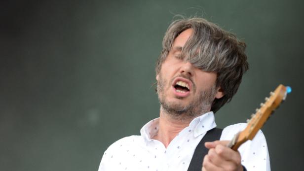 Ein Mann mit grauen Haaren spielt E-Gitarre und singt.