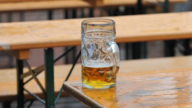 Ein halbes Maß Bier steht auf einem Holztisch.