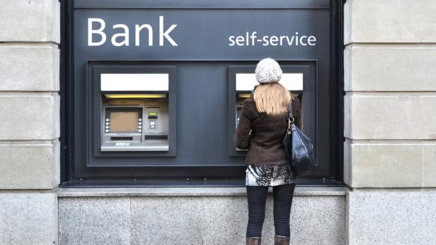 Eine Frau benutzt einen Geldautomaten einer Bank.