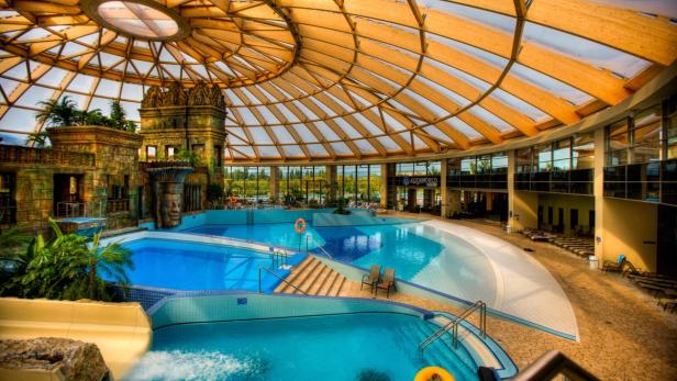 VAMED Vitality World erweitert das Angebot: Eine n Innenansicht des Aquaworld Budapest mit Schwimmbecken und Wasserrutsche.