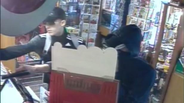 Zwei Personen stehen an einer Kasse in einem Geschäft.