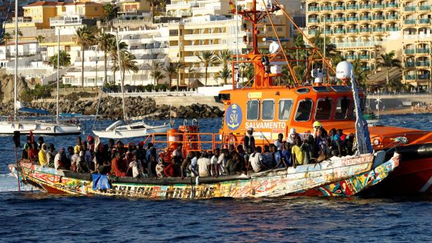 Group of migrants in a wooden boat are towed by a Spanish coast guard vessel to the port of Arguineguin
