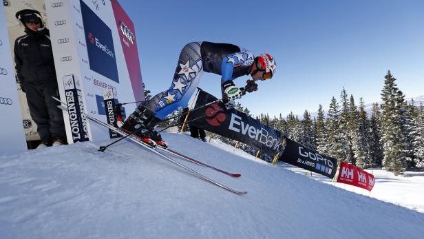 Ein Skirennläufer fährt einen Hang hinunter, umgeben von Werbebannern.