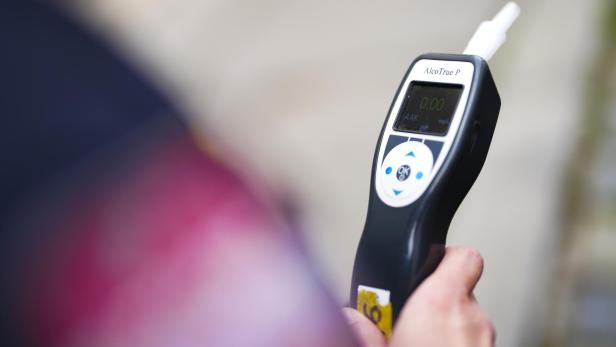 Eine Person hält ein Alkoholmessgerät in der Hand.