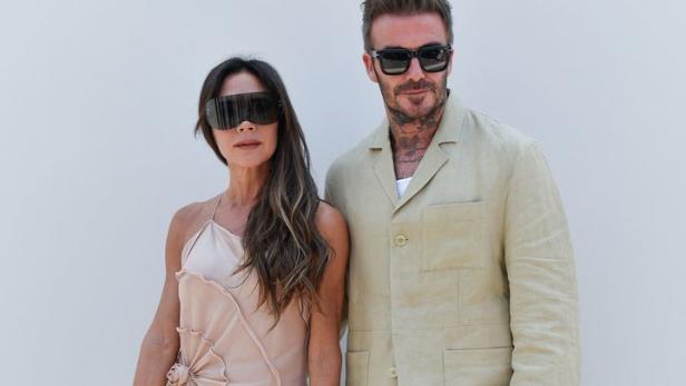 Victoria und David Beckham posieren vor einer weißen Wand.
