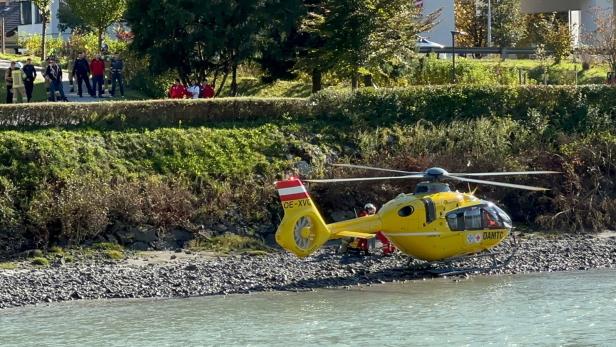 Ein gelber Rettungshubschrauber des ÖAMTC steht am Ufer eines Flusses.