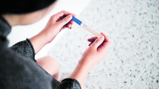 Frau hält Schwangerschaftstest in der Hand