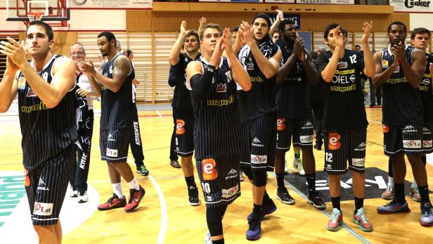Eine Basketballmannschaft applaudiert auf dem Spielfeld.
