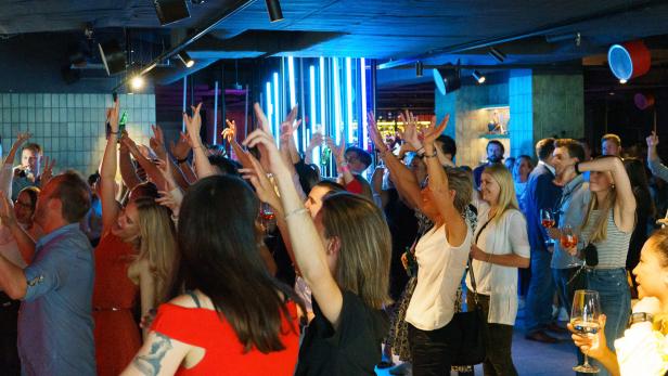 Eine feiernde Menschenmenge mit erhobenen Händen in einem Club.