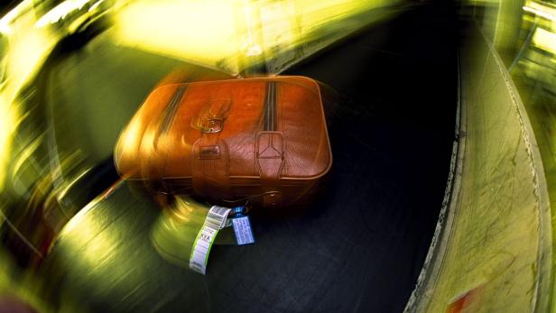 Ein brauner Lederkoffer auf einem Gepäckband mit Unschärfeeffekt.