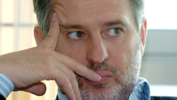 Ein Mann mit Bart blickt nachdenklich zur Seite.