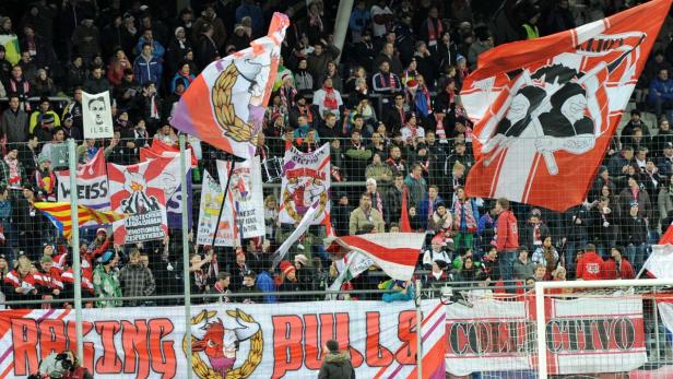 Zuschauer mit Fahnen und Bannern bei einem Fußballspiel.