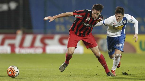 Zwei Fußballspieler kämpfen um den Ball auf dem Spielfeld.