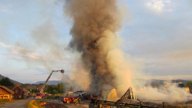 Ein Gebäude steht in Flammen, während Feuerwehrleute versuchen, den Brand zu löschen.