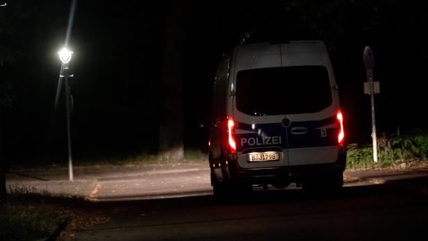 Ein Polizeiwagen steht nachts auf einer dunklen Straße in Berlin.