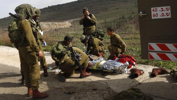 Soldaten leisten einem Verletzten auf einer Trage Erste Hilfe.