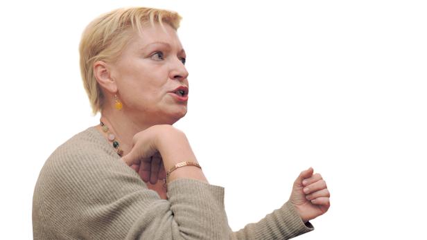 Eine Frau mit blonden, kurzen Haaren gestikuliert und spricht.