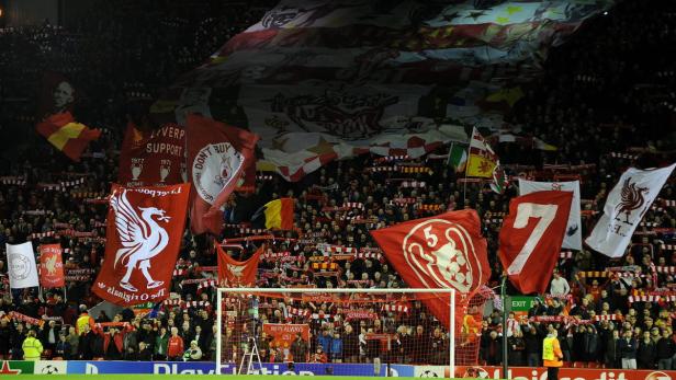 Fußballfans schwenken Fahnen und unterstützen den FC Liverpool im Stadion.