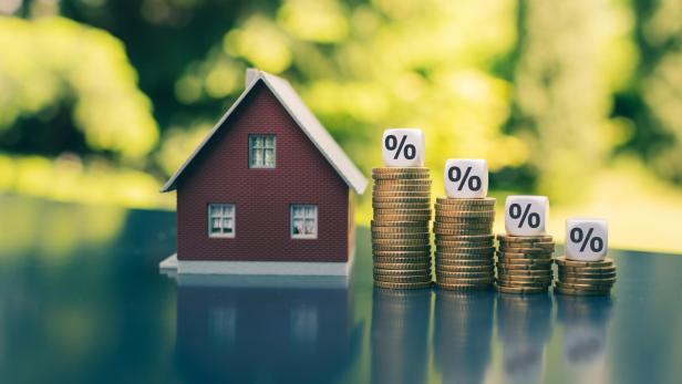 Symbol for decreasing interest rates. Dice with percentage symbols on decreasing high stacks of coins next to a model house. Symbol for decreasing interest rates. Dice with percentage symbols on decreasing high stacks of coins next to a model house.