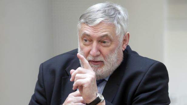 Ein älterer Mann mit Bart gestikuliert mit dem Finger.