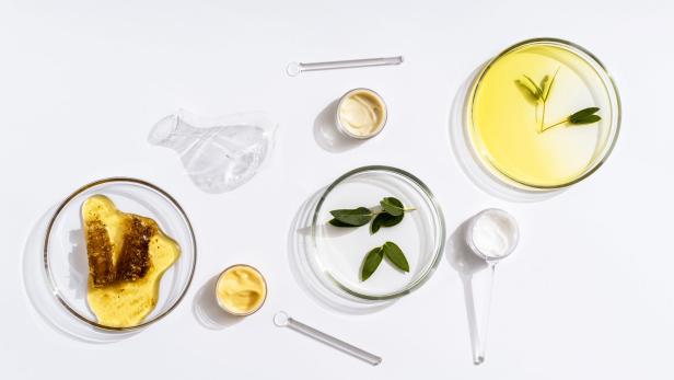 Petrischalen mit Pflanzenextrakten und Cremes auf einem weißen Hintergrund.