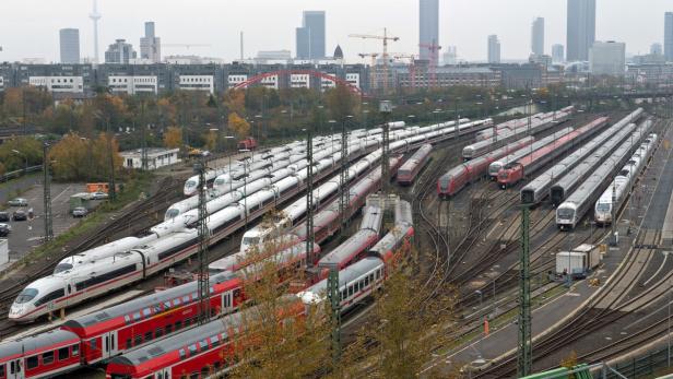 Viele Züge stehen auf einem Abstellgleis vor der Skyline einer Stadt.