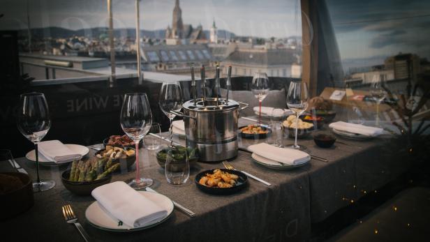Ein Tisch mit Fondue-Zutaten und Blick auf Wien.