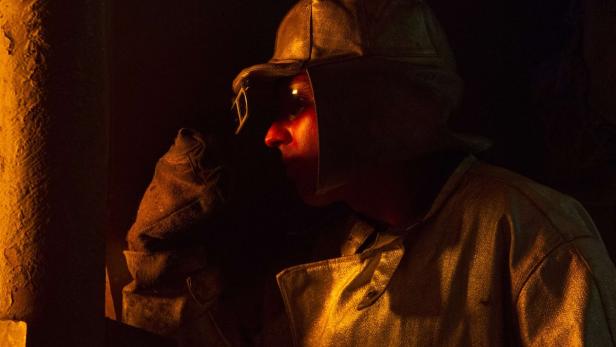 Ein Arbeiter mit Schutzkleidung und Schutzbrille in einer dunklen Umgebung.