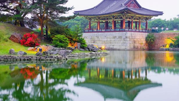 Ein traditioneller koreanischer Pavillon spiegelt sich in einem ruhigen Teich.