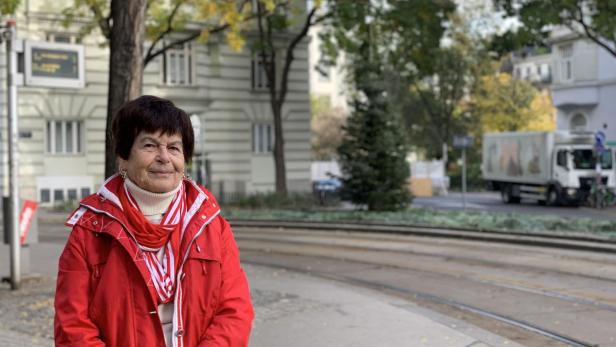 Irene Gründler in roter Jacke bei einer Straßenbahnstation